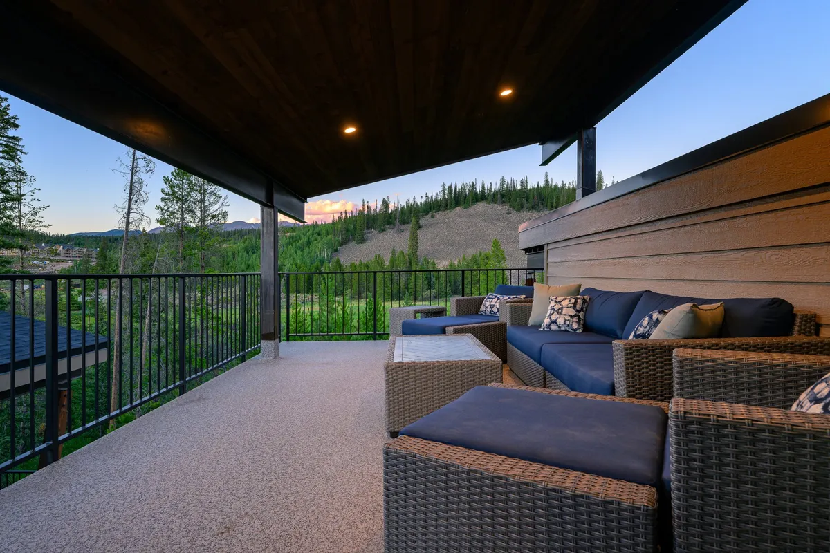 An exterior setting with a comfortable seating area on a rooftop or elevated deck, positioned to capture sweeping mountain views and a peaceful evening sky. The setup encourages both tranquil solitude and social gatherings.