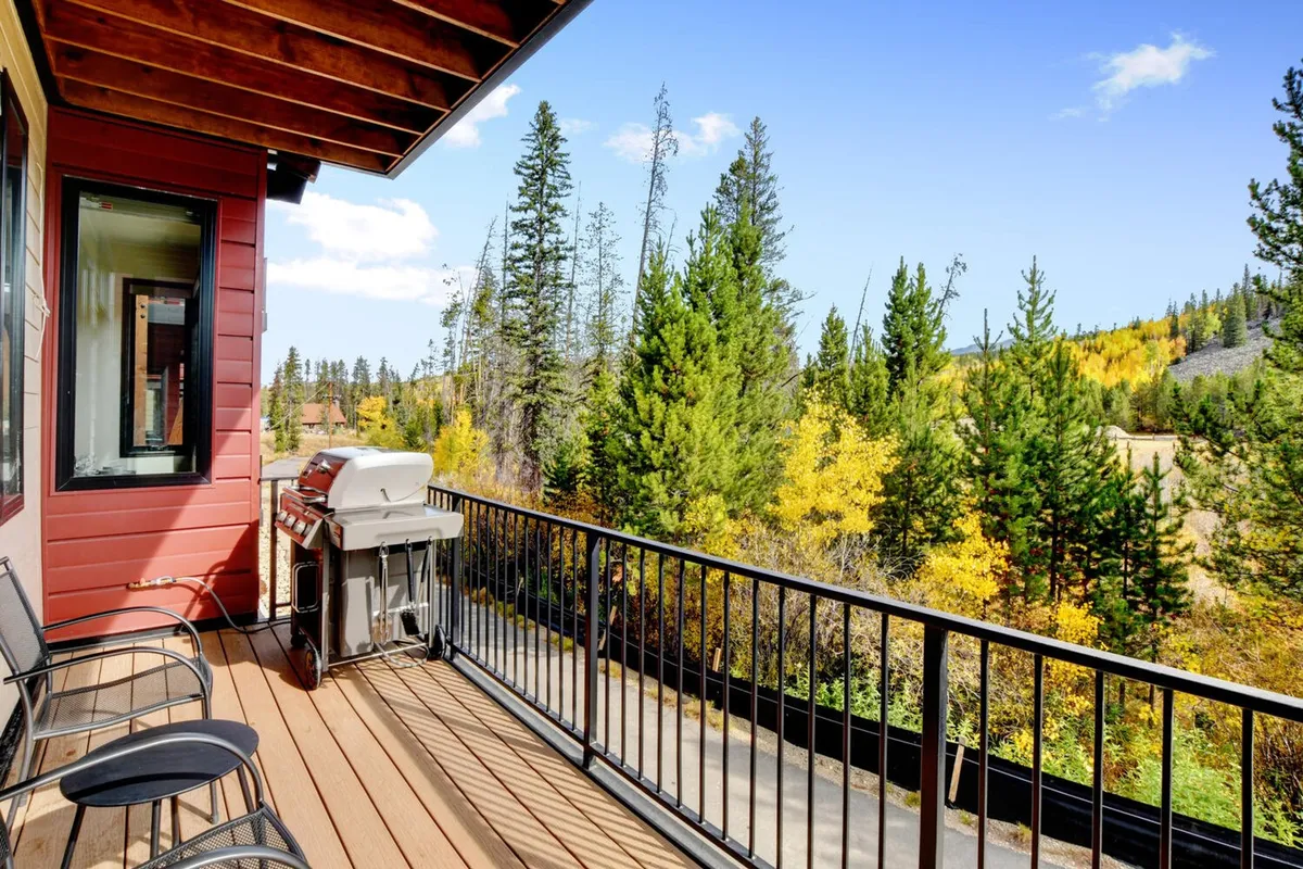 An outdoor balcony set against a backdrop of trees, featuring a gas grill and seating area. The setup is perfect for barbecues, casual outdoor dining, or relaxing with a morning coffee while soaking in the peaceful views.