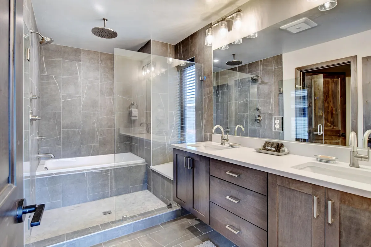 A sophisticated en suite bathroom featuring a freestanding bathtub, spacious vanity, large mirror, and a glass shower area. Soft natural light and sleek finishes create a spa-like atmosphere, perfect for relaxation and self-care.