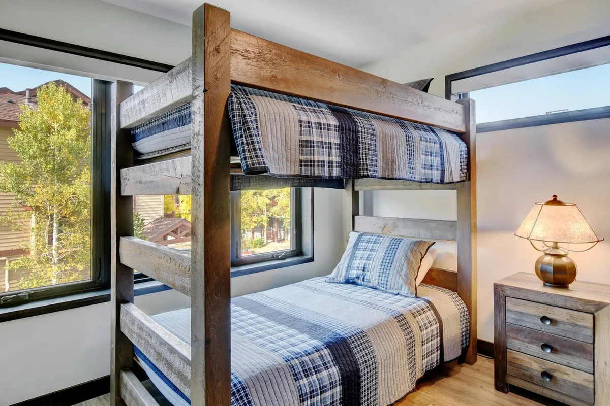 A playful and inviting interior bedroom with a bunk bed, window views, a table lamp, and a nightstand. The scene suggests a child-friendly environment ideal for play, reading, and family bonding.
